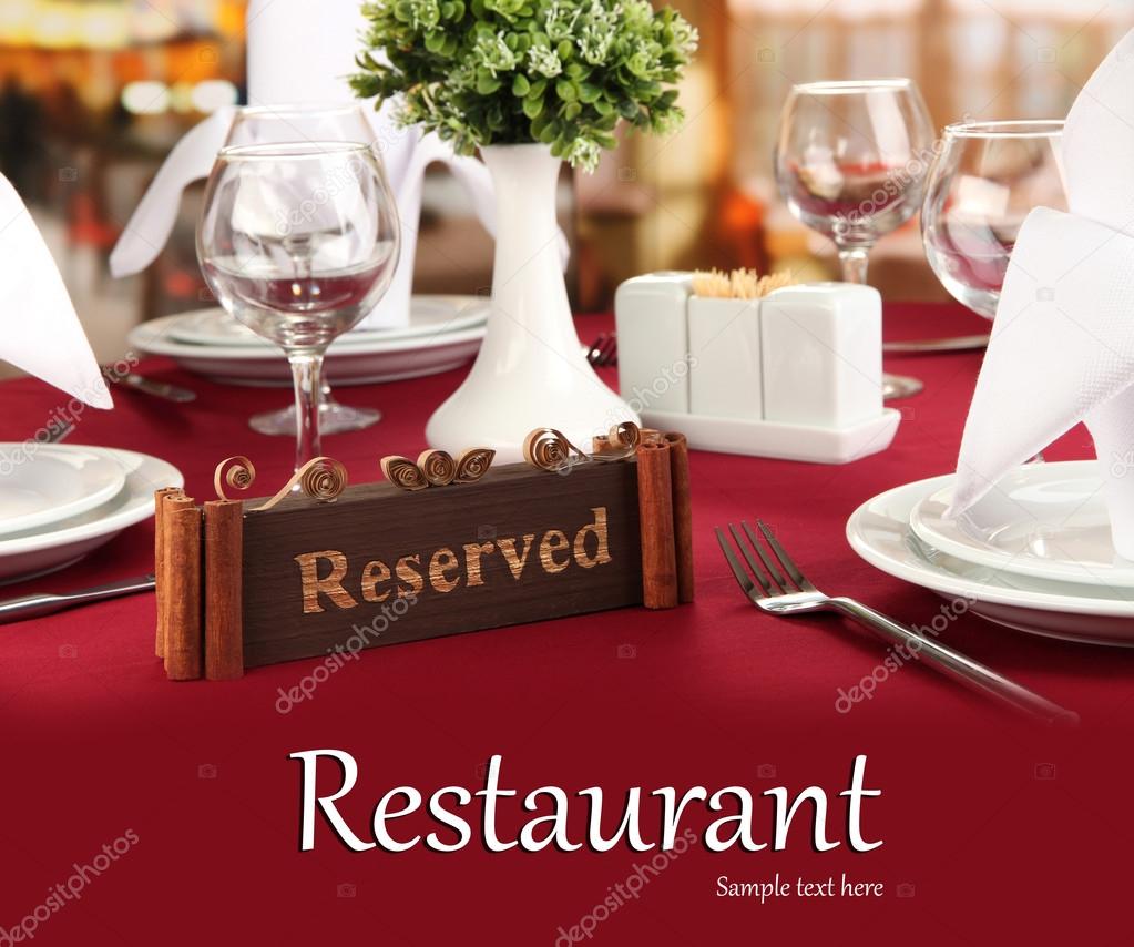 Reserved sign on restaurant table with empty dishes and glasses