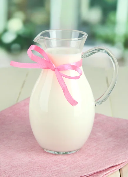 Pitcher of milk on table in room — Stock Photo, Image