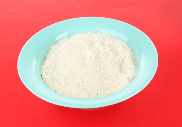 Powdered milk in bowl for baby on red background — Stock Photo, Image