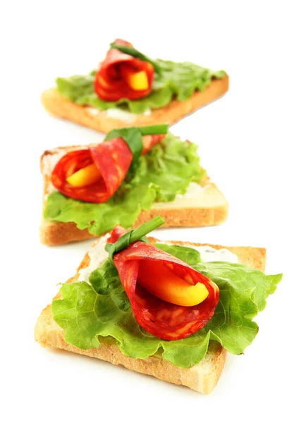 Salami rolls with paprika pieces inside, on roasted bread, isolated on white — Stock Photo, Image