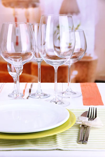 Table setting with glasses for different drinks on table on room background — Stock Photo, Image