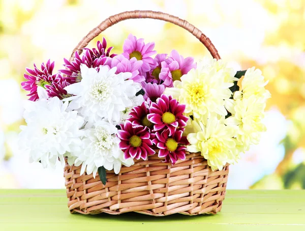 Boeket van mooie chrysanten in rieten mand op tafel op lichte achtergrond — Stockfoto