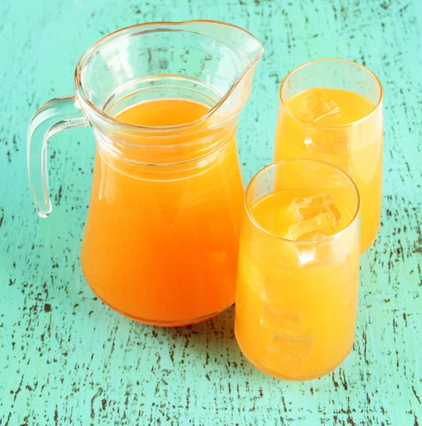 Bicchieri e brocca di succo d'arancia su fondo di legno blu — Foto Stock