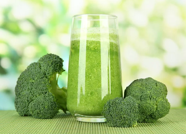 Bicchiere di succo di broccolo, su tappetino di bambù, su fondo verde — Foto Stock