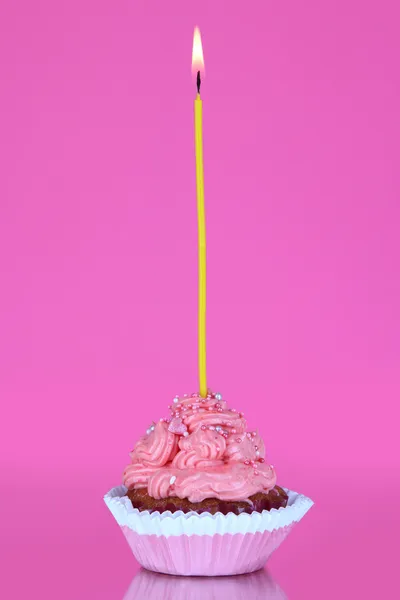 ピンクの背景の蝋燭と美しいカップケーキ — ストック写真