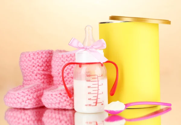 Bottle with milk and food for babies on beige background — Stock Photo, Image