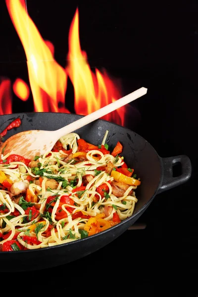 Fideos con verduras en wok sobre fondo de fuego — Foto de Stock