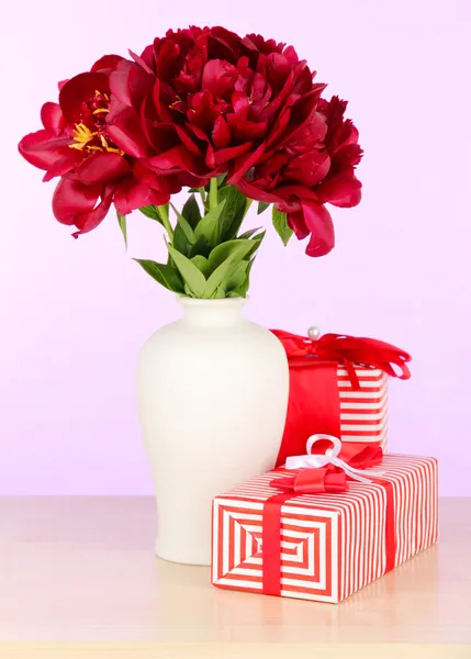 Beautiful peonies in vase on table on white background — Stock Photo, Image