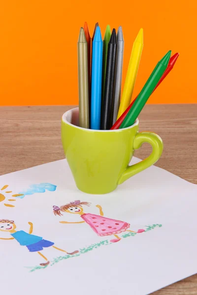 Buntstifte in Tasse auf Tisch auf orangefarbenem Hintergrund — Stockfoto