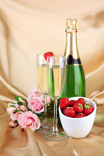 Romantic still life with champagne, strawberry and pink roses, on color fabric background — Stock Photo, Image