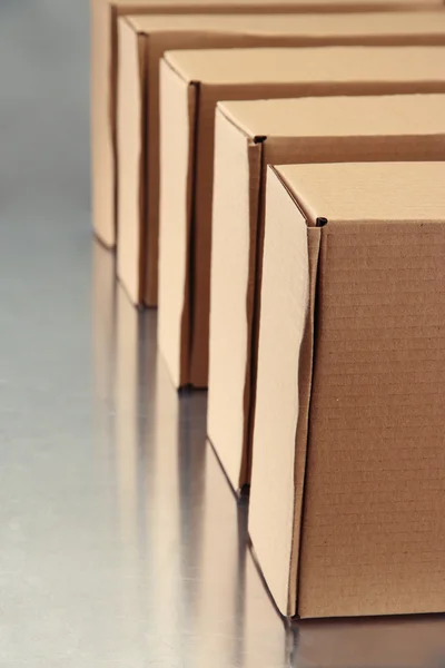 Cardboard boxes on conveyor belt, on grey background — Stock Photo, Image