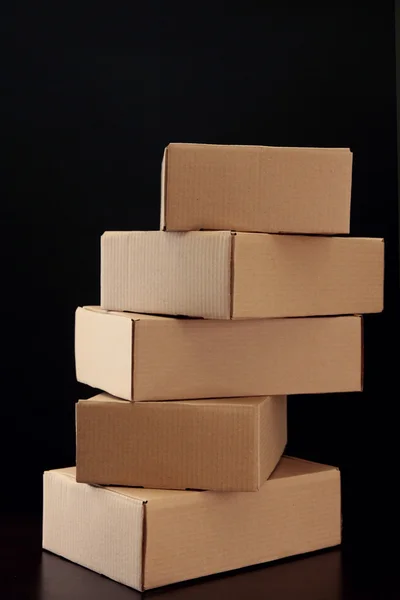 Коробки для посылок на деревянном столе, на черном фоне — стоковое фото