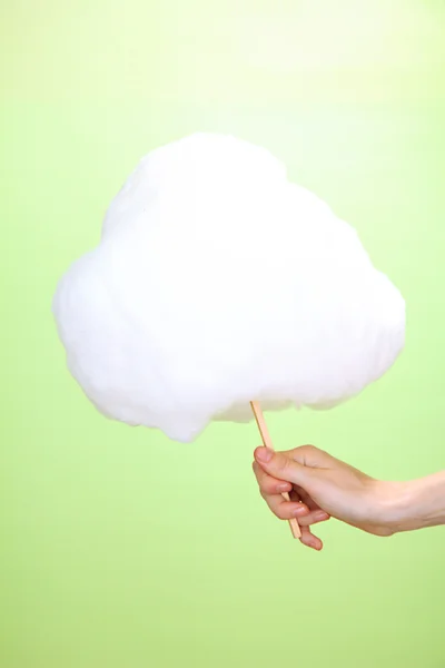 Hand holding stick with cotton candy, on color background — Stock Photo, Image