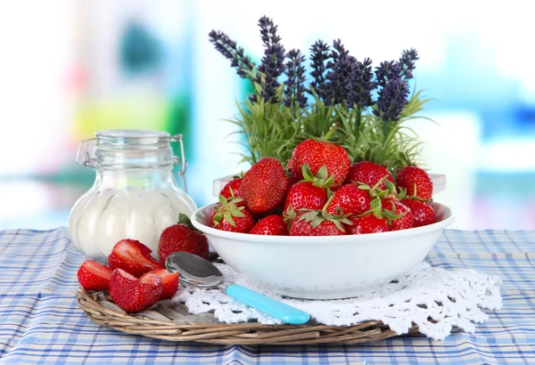 Strawberries in plate on wicker stand on table on wooden background — Stock Photo, Image