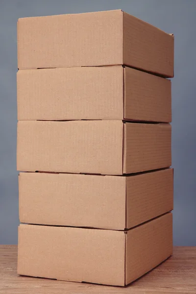 Коробки для посылок на деревянном столе, на сером фоне — стоковое фото