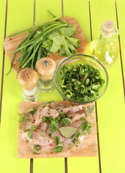 Carne de frango em placa de vidro, ervas e especiarias em mesa de madeira — Fotografia de Stock