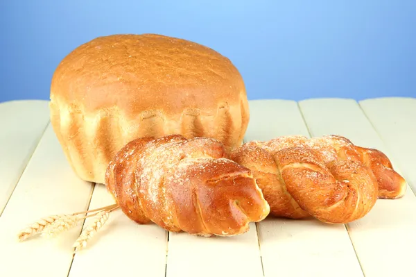 Σύνθεση με ψωμί και ψωμάκια στο ξύλινο τραπέζι, σε φόντο χρώμα — Φωτογραφία Αρχείου