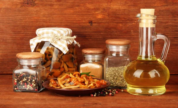 Composition of delicious marinated mushrooms, oil and spices on wooden table on wooden background — Stock Photo, Image