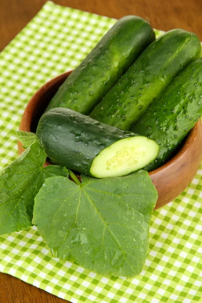 Tasty green cucumbers on color napkin, on wooden background — Stock Photo, Image