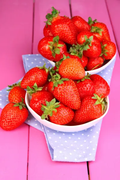 Färska jordgubbar i skål på rosa trä bakgrund — Stockfoto