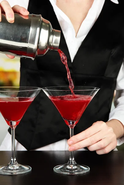Barmen hand with shaker pouring cocktail into glasses, on bright background — Stock Photo, Image