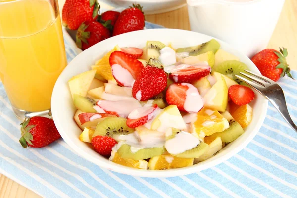 Полезный фруктовый салат из свежих фруктов и ягод в миске на салфетке на деревянном столе крупным планом — стоковое фото