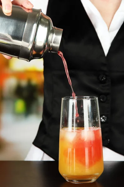 Barmen mano con agitador verter cóctel en el vaso, sobre fondo brillante — Foto de Stock
