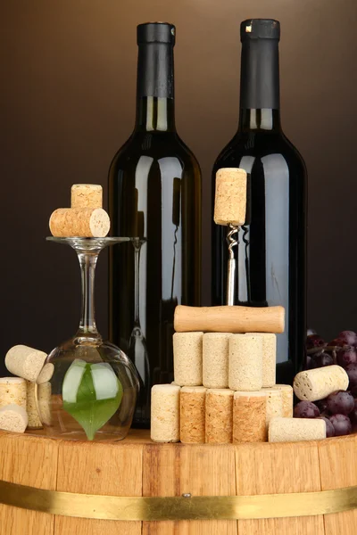 Wine and corks on barrel on brown background — Stock Photo, Image