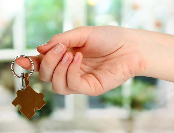 Key with leather trinket in hand on window background — Zdjęcie stockowe