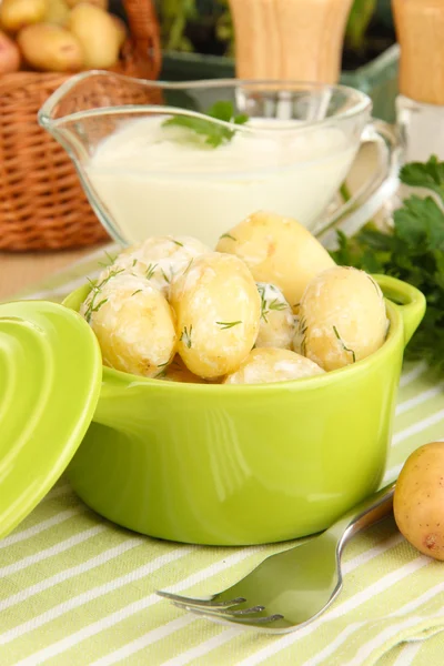 Tender young potatoes with sour cream and herbs in pan on wooden table close-up — Stock Photo, Image