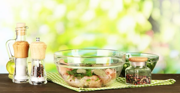 Carne de pollo en tazón de cristal, hierbas y especias en la mesa sobre fondo natural —  Fotos de Stock