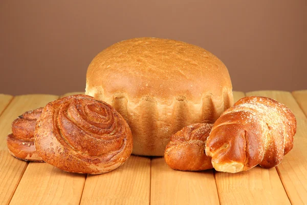 Composition with bread and rolls on wooden table, on color background — Stock Photo, Image