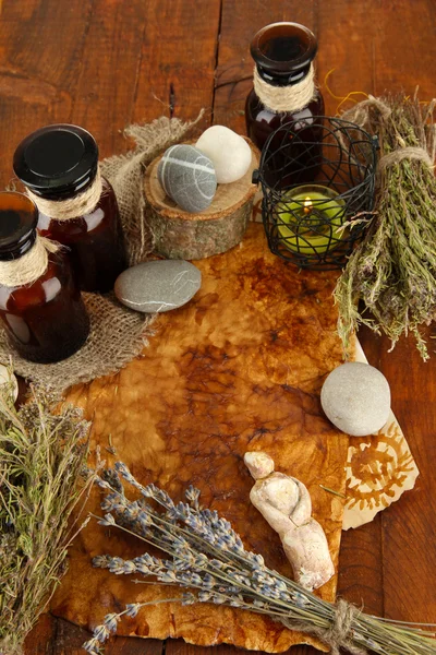 Composition with old papers, herbs, stones and bottles with symbols on wooden background — Stock Photo, Image