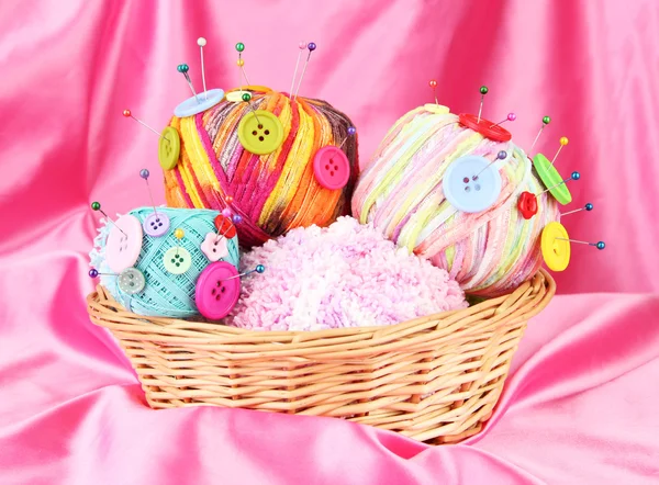 Colorful buttons and multicolor wool balls in wicker basket, on color fabric background — Stock Photo, Image