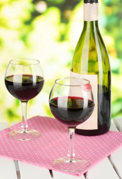 Dwie szklanki wina i butelka na stole na tle przyrody — Zdjęcie stockowe
