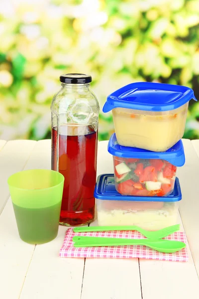 Leckeres Mittagessen in Kunststoffbehältern, auf Holztisch vor hellem Hintergrund — Stockfoto