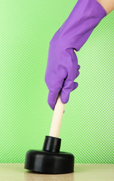 Toilet plunger in hand on green background — Stock Photo, Image