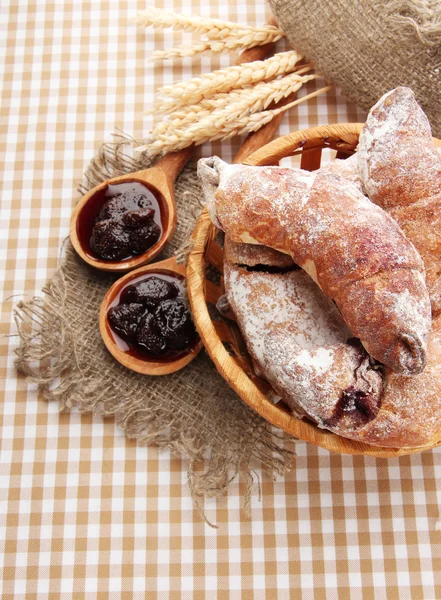 Prove croissants em cesta e geléia em toalha de mesa — Fotografia de Stock
