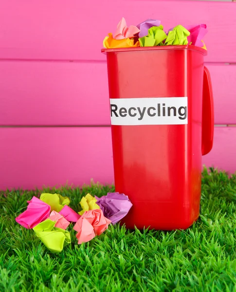 Reciclagem bin com papéis na grama em fundo rosa — Fotografia de Stock