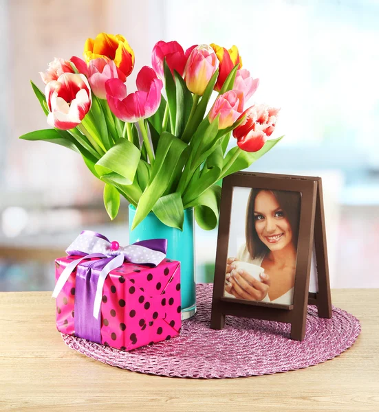 Beautiful tulips in bucket with gifts on table in room — Stock Photo, Image
