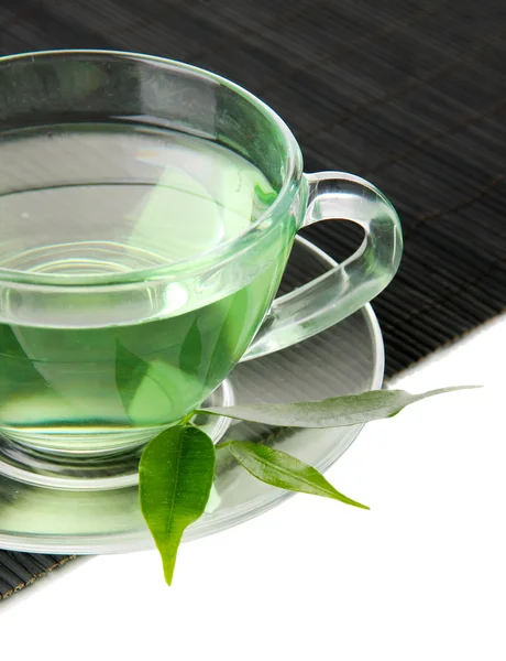 Taza transparente de té verde en estera de bambú, aislada en blanco — Foto de Stock