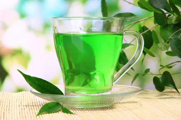 Taza transparente de té verde sobre estera de bambú, sobre fondo natural —  Fotos de Stock