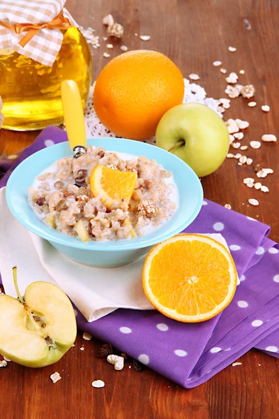 Harina de avena útil en un tazón con fruta en una mesa de madera —  Fotos de Stock