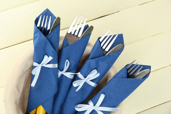 Gafflar och knivar insvept i blå pappersservetter, på färg trä bakgrund — Stockfoto