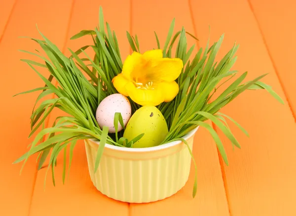 Paskalya yumurtası kase çim turuncu ahşap masa üzerinde kapat — Stok fotoğraf