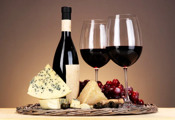 生活依然精致的红酒、 奶酪和米色背景上的木桌上的柳条托盘上的葡萄 — 图库照片