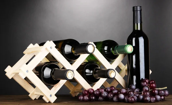 Botellas de vino colocadas sobre soporte de madera sobre fondo gris —  Fotos de Stock