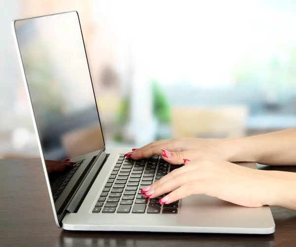 Female hands typing on laptop, on bright background — Stock Photo, Image