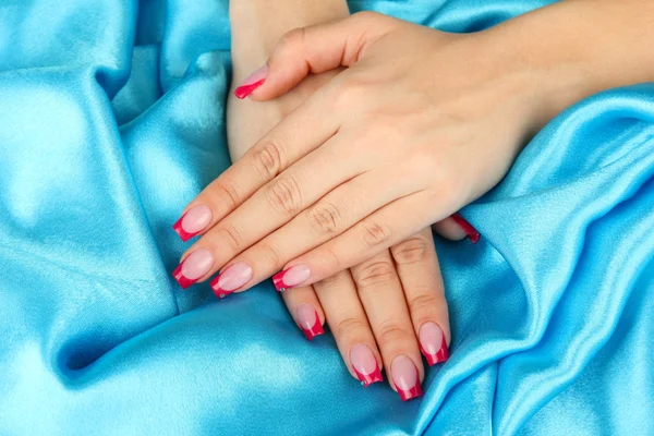 Female hands on color fabric background — Stock Photo, Image