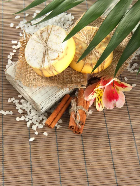 Hand-made soap and sea salt on grey bamboo mat — Stock Photo, Image